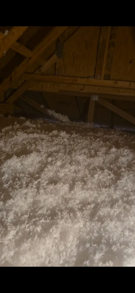 An attic floor covered in fresh white blown-in insulation, like snow